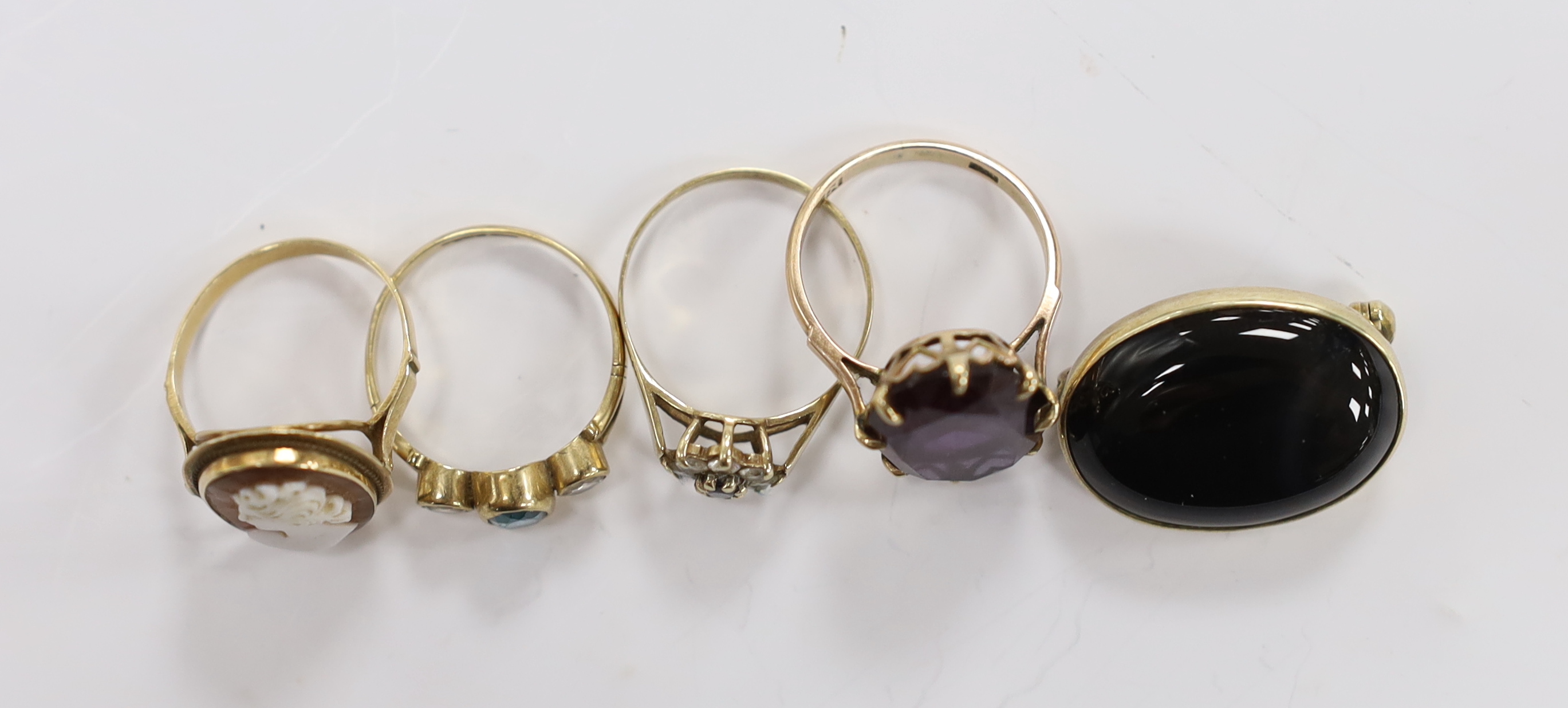 Two 14k and gem set rings, including cameo shell and synthetic colour change corundum, two 9ct gold and gem set rings and a cabochon set yellow metal oval brooch.